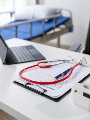 A doctor's office with a laptop, stethoscope, and a clipboard. The laptop is open to a medical document