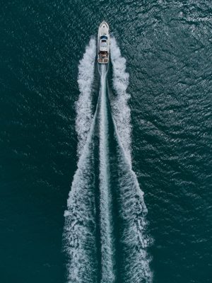 Aerial top down view of white speed motor boat on open sea at summer day