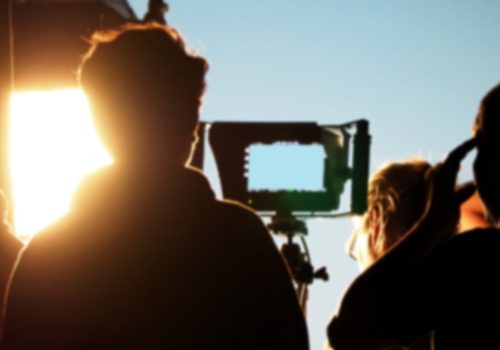 Blurry images of silhouette people film crew team working behind the scenes for shooting video production with professional equipment camera and lighting in the studio.