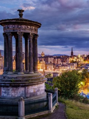 Calton Hill Folly and Edinburgh skyline lit up at dawn.