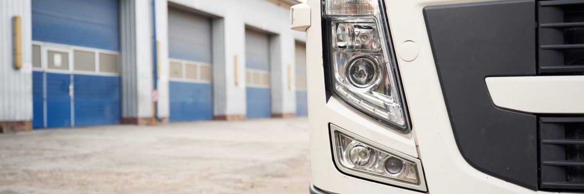 Front particle view of truck that is parked outdoors near garage.