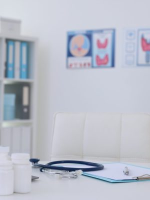 Laptop, medicine, stethoscope and clipboard on desk in doctor's office