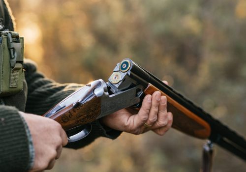 Crop unrecognizable male hunter loading cartridges in hunting rifle for capturing or killing wild animals in woods