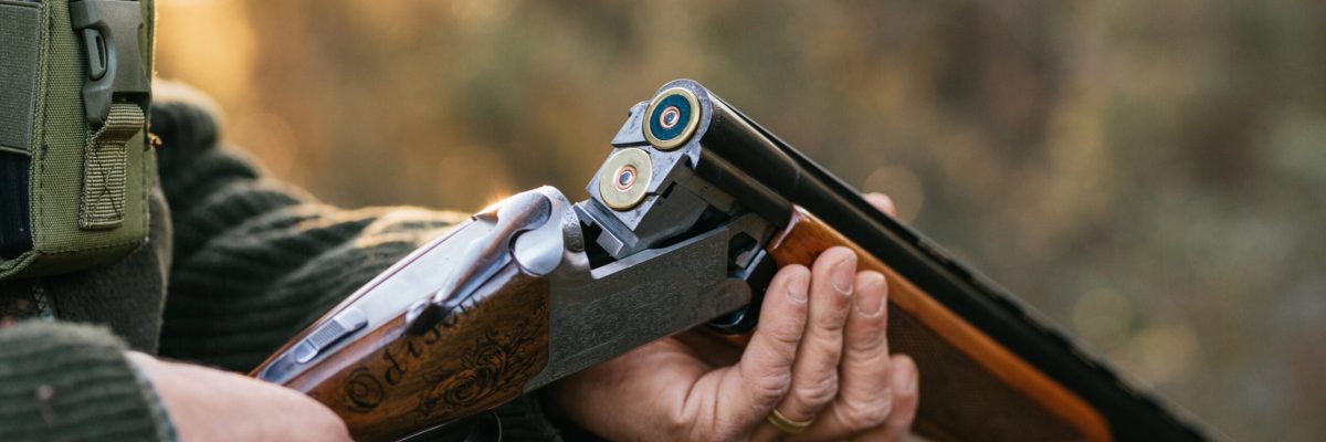 Crop unrecognizable male hunter loading cartridges in hunting rifle for capturing or killing wild animals in woods