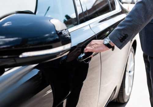 partial view of businessman opening car door
