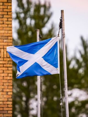 The Scotland flag blowing in the wind in front of a red brick building