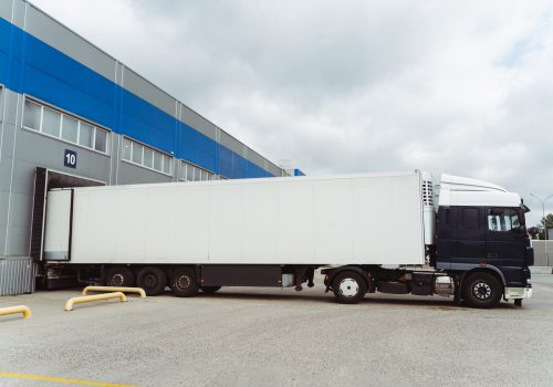 Truck parked near cargo terminal, loading goods on the street near warehouse. Concept of transportation, cargo transportation