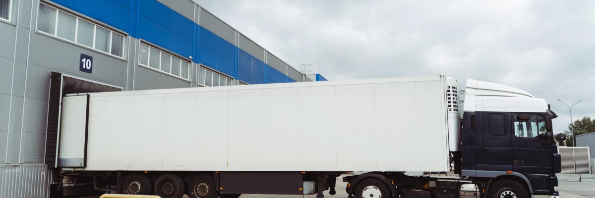 Truck parked near cargo terminal, loading goods on the street near warehouse. Concept of transportation, cargo transportation