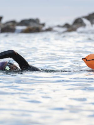 Portrait of a woman swimming in open water with wetsuit and buoy